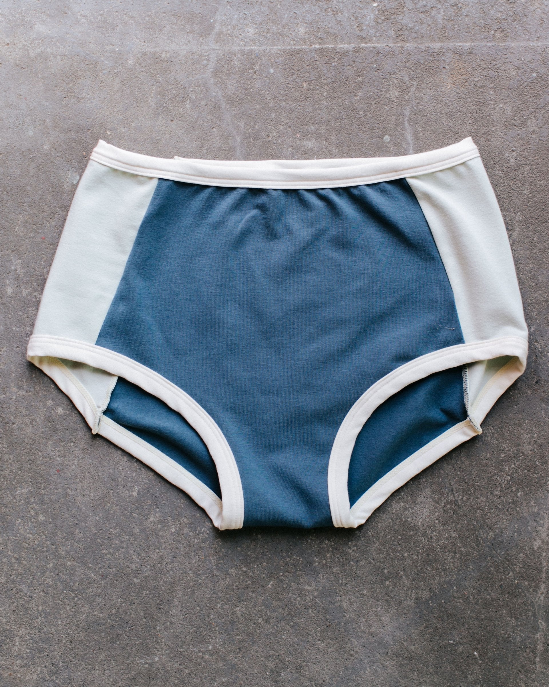 Flat lay of Thunderpants Organic Cotton Original style underwear with Stormy Blue front and back panels and Dried Sage side panels.
