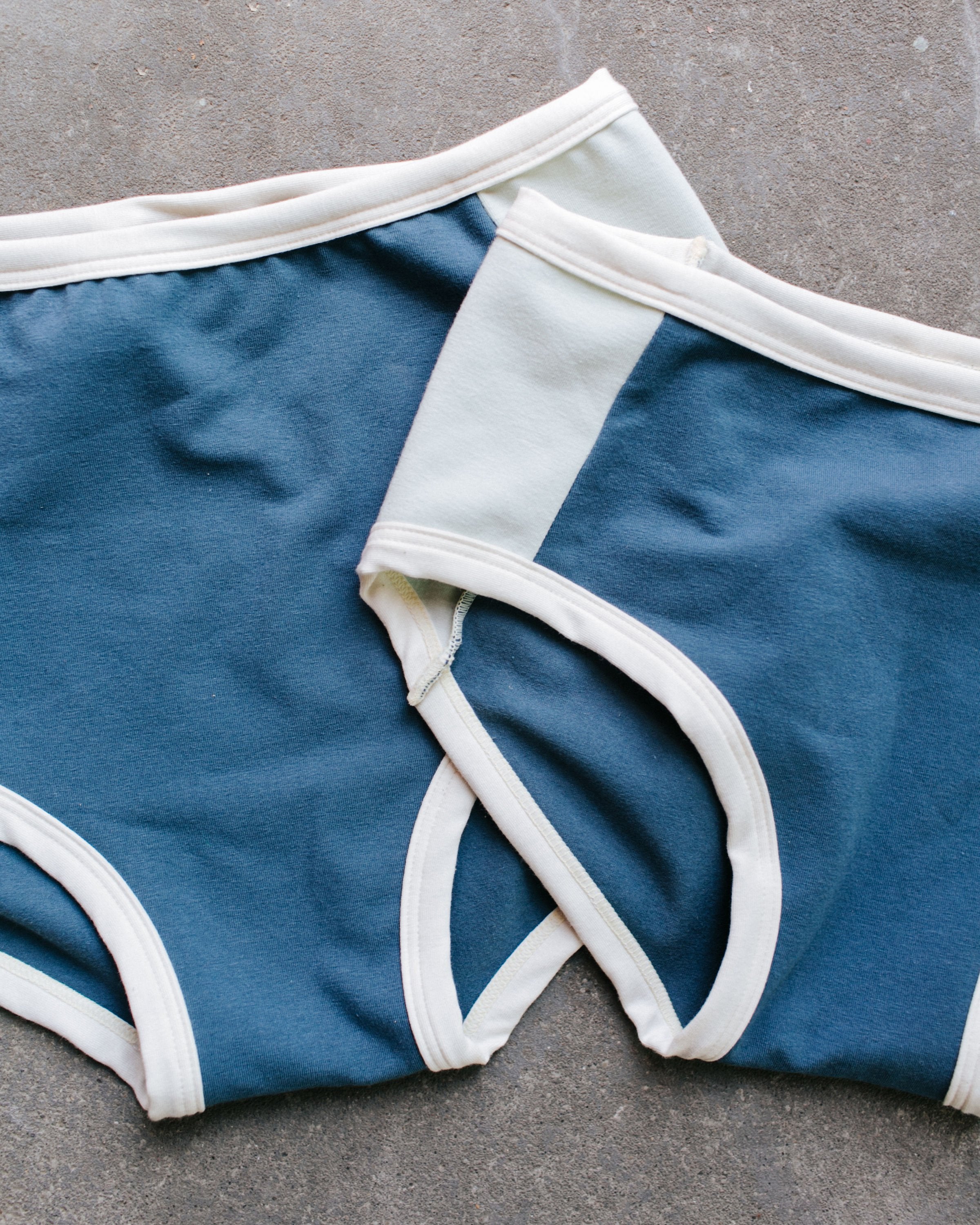 Close up of Thunderpants organic cotton Original style underwear and Hipster style underwear with Stormy Blue front and back panels and Dried Sage side panels.