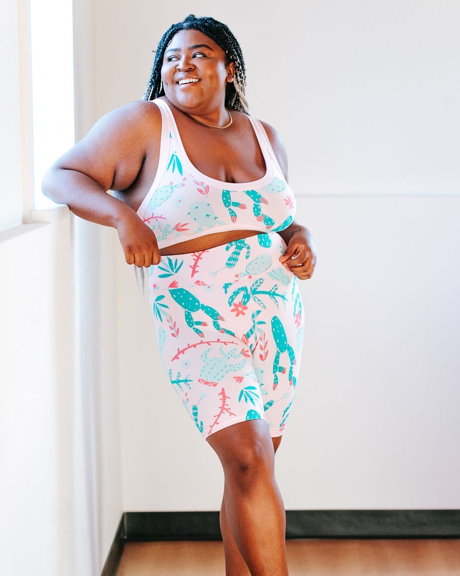 Beautiful plus-sized model wearing Thunderpants organic cotton High Rise Bike Shorts and Bralette in a pink and green cactus print.