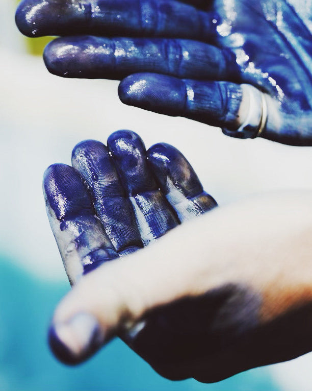 Hands covered in bright blue indigo dye.